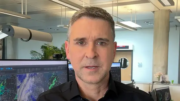 Jörg Heidermann im Büro vor Bildschirmen mit Wettersimulationen.